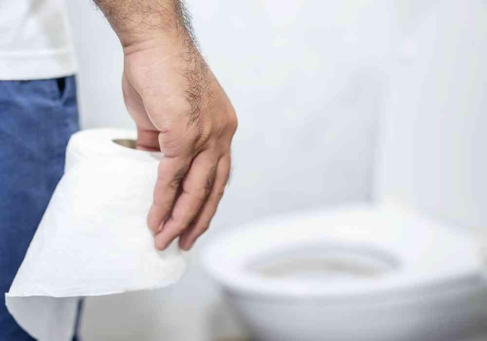 man holding toilet paper in bathroom