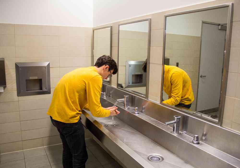 Man washing hands in public bathroom